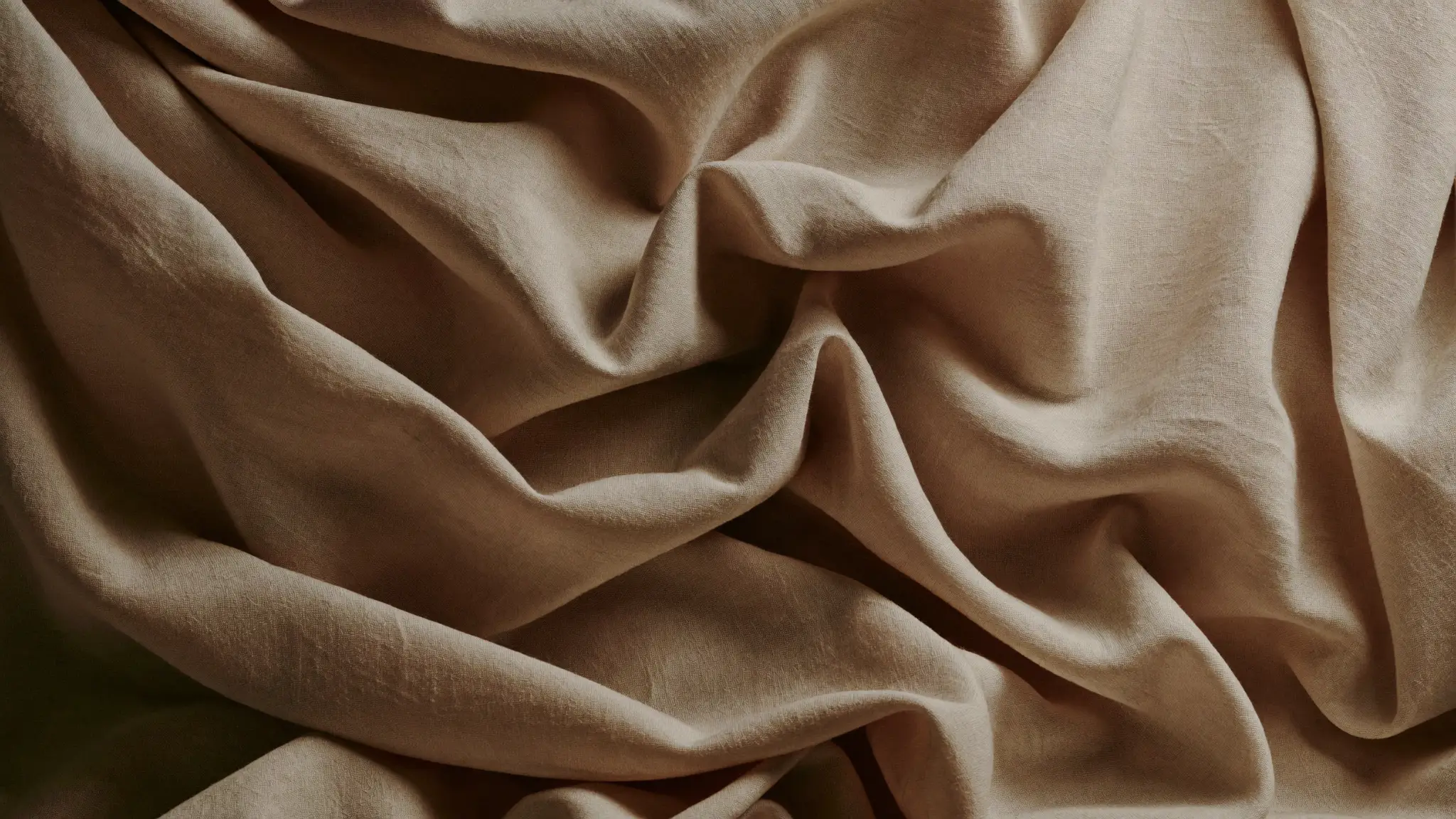Heavy bone linen and raw silk falling in deep sculptural folds under clay-toned light