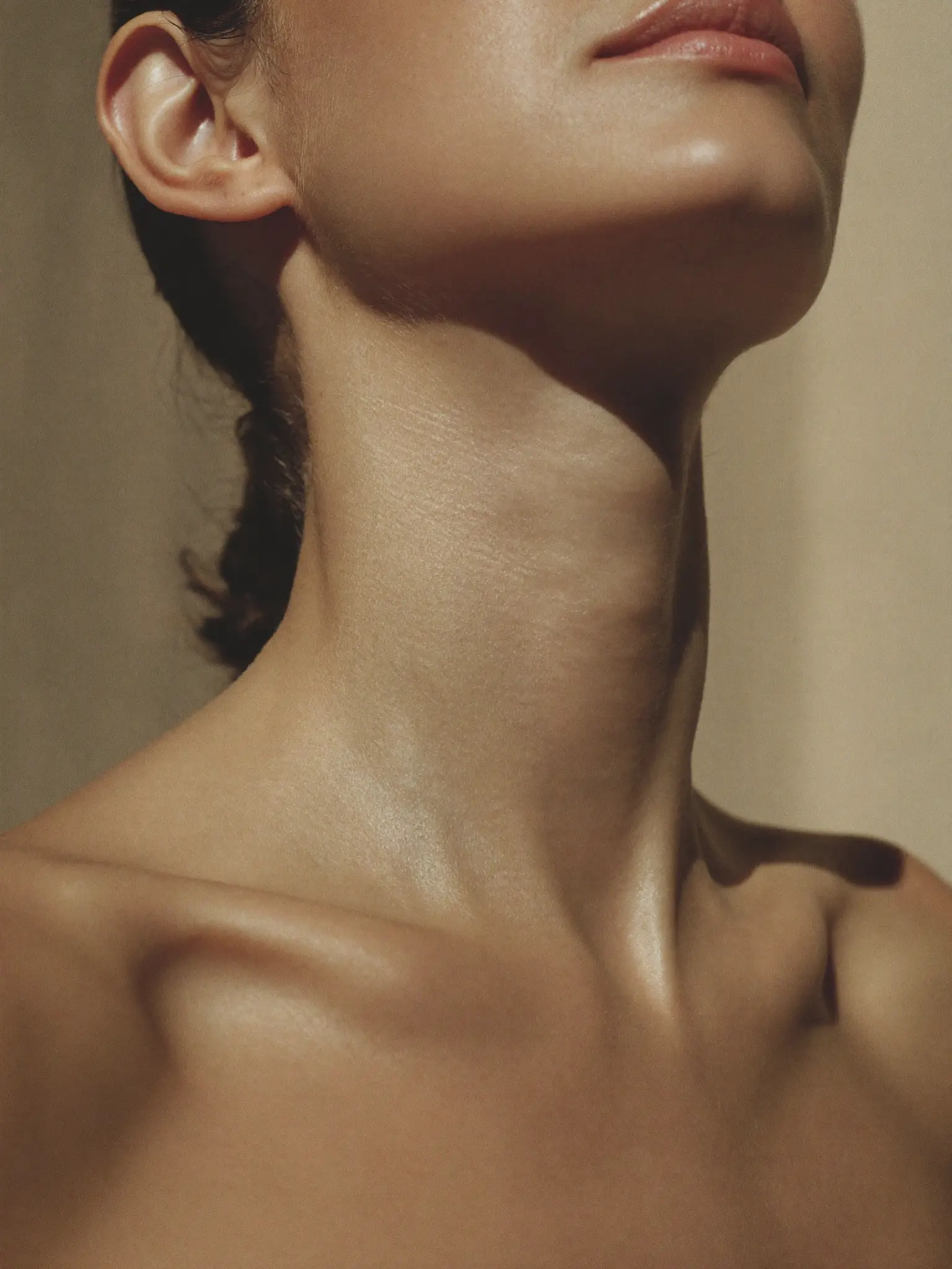Close-up of a person’s lower face and neck in warm light.