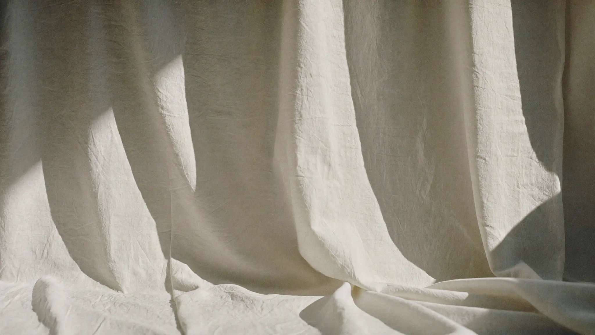 Folds of undyed bone linen catching soft daylight